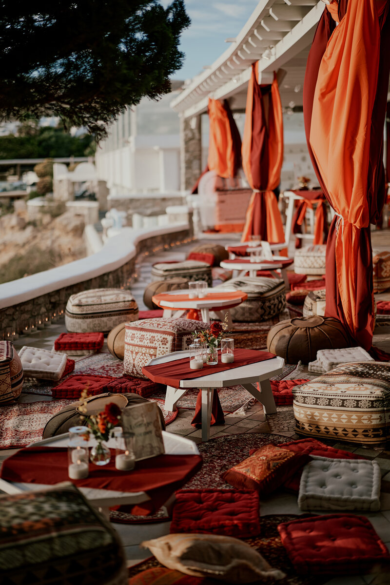 Middle eastern inspired lounge corner of a wedding venue with carpets, pillows and candles set up for a pre wedding event celebration in Mykonos