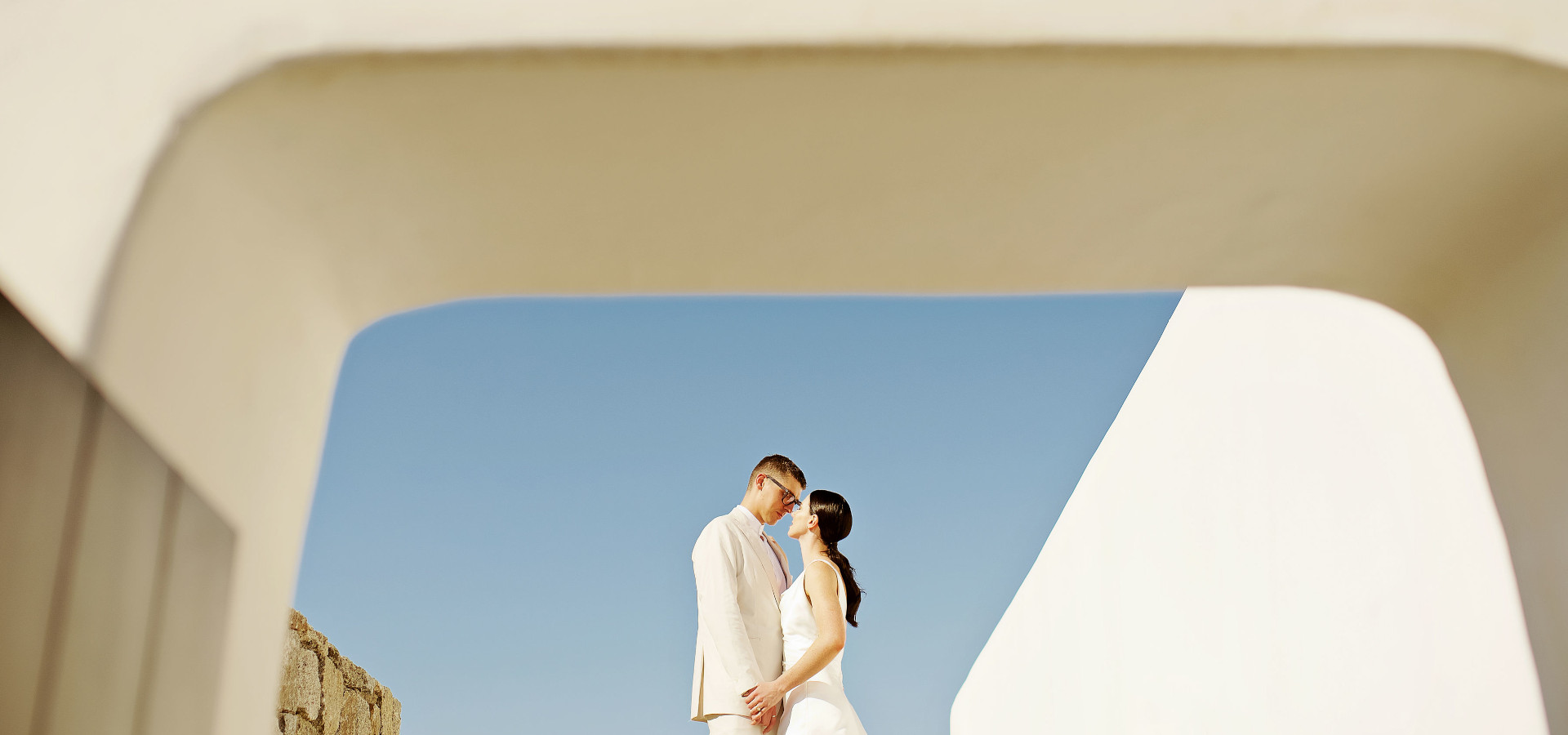 A bride and groom standing in an archway at a Mykonos destination wedding