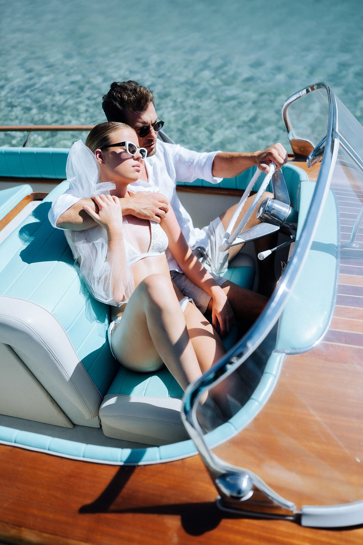 Stylish couple during a luxury Mykonos wedding boat ride, surrounded by crystal-clear Aegean waters and effortless Greek island elegance
