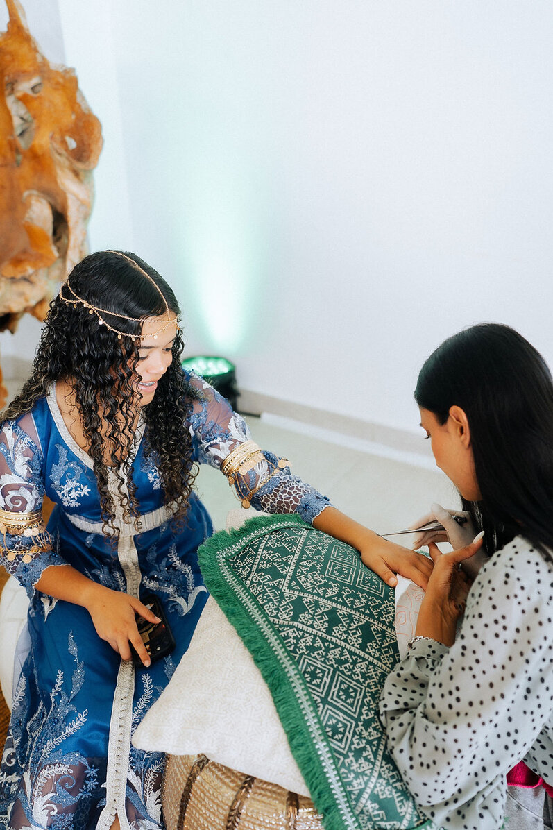 Bride during a luxury Mykonos wedding henna ceremony with traditional attire, cultural jewelry, and intricate henna application before the wedding celebration.