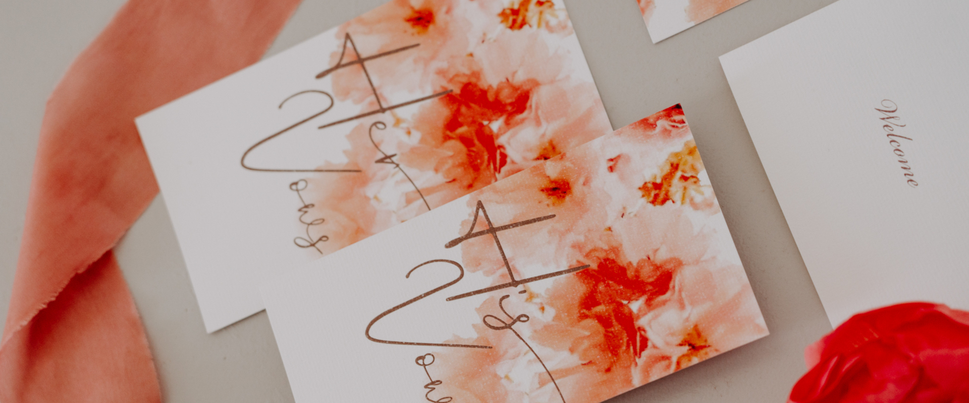 Elegantly placed coral themed wedding stationary on a white canvas, for couples dream wedding in Mykonos.