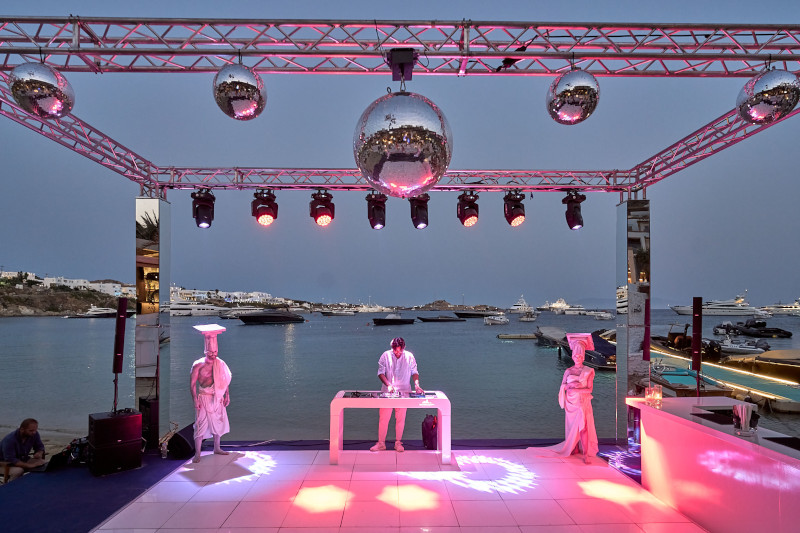 A luxurious wedding stage adorned with dazzling lights and a skilled DJ, creating an enchanting ambiance for a Mykonos wedding.