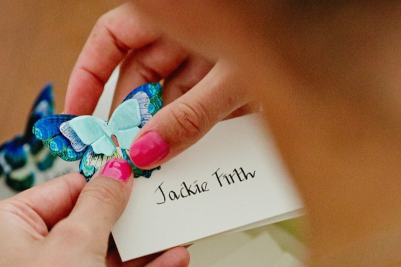 Woman holding butterfly wedding seating card rsvp services for Mykonos wedding guest management.