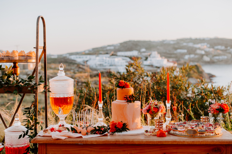 A beautifully arranged dessert table with an assortment of sweet treats and wedding cake, creating a romantic atmosphere for a luxurious Mykonos wedding