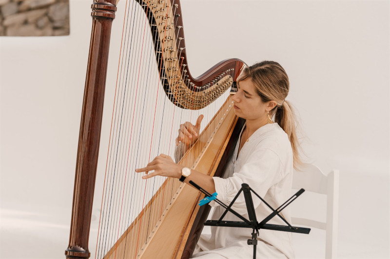 A harpist gracefully playing the harp in for a luxury ceremony, providing enchanting wedding entertainment in Mykonos.