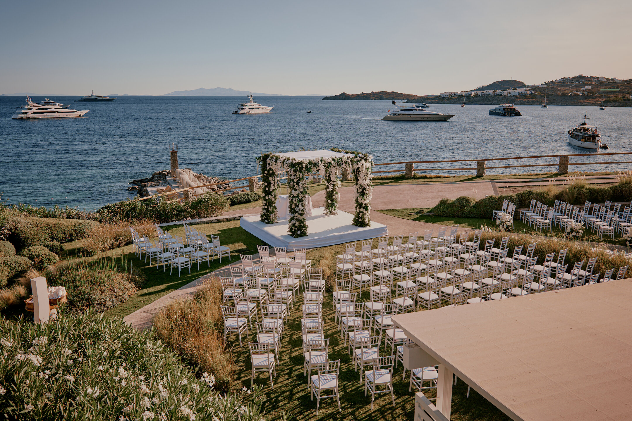 Luxury destination wedding ceremony in Mykonos with elegant seating, floral wedding canopy, and panoramic Aegean Sea views at an exclusive Greek island venue
